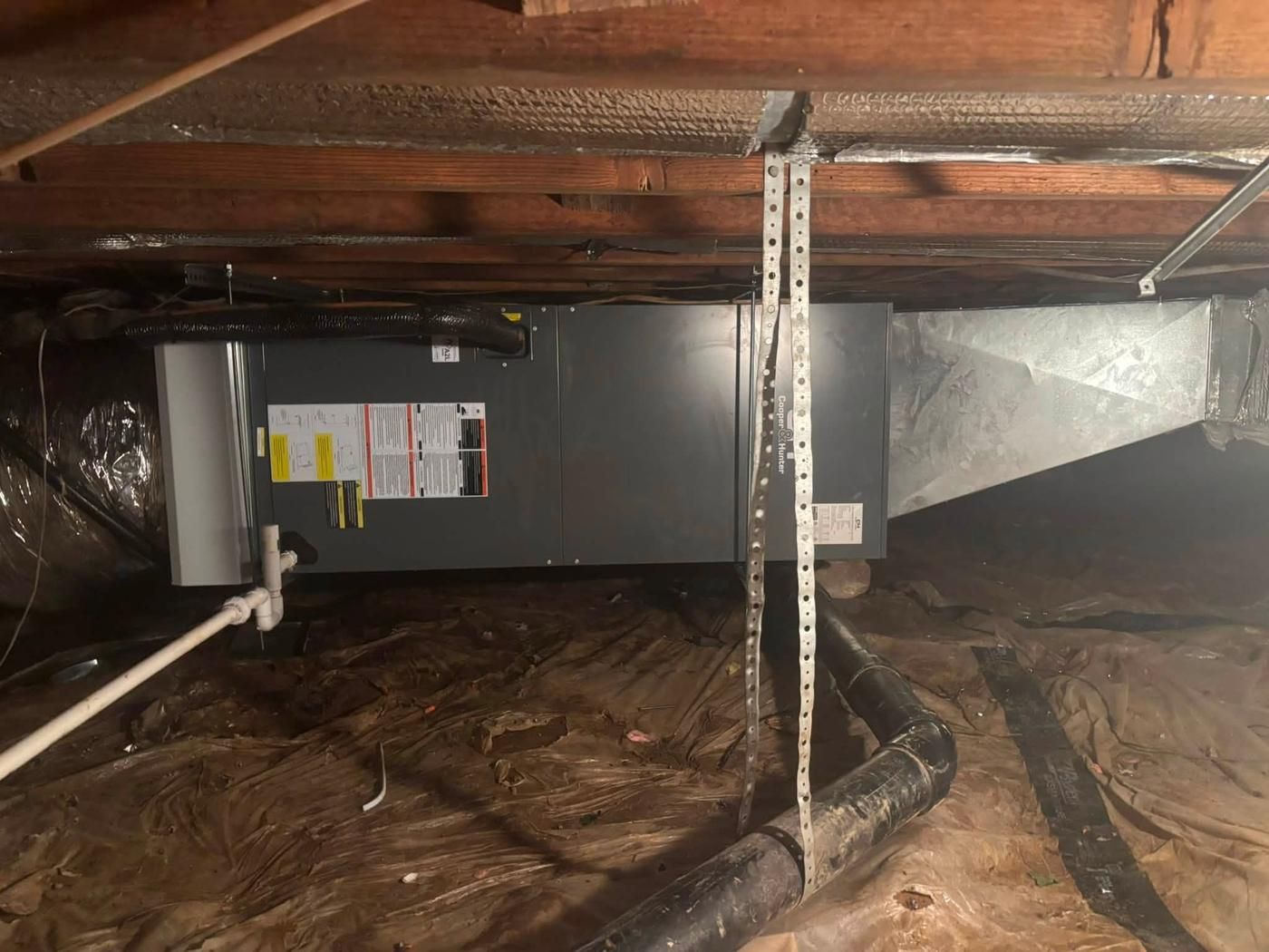 An air handler hung and strapped in a crawlspace