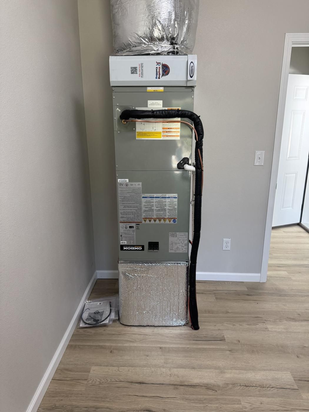 Oxbox air handler standing in the corner of a finished room with insulated duct above